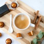 Elegant coffee setup with Nespresso capsules, cinnamon, and eucalyptus, perfect for a stylish coffee break.